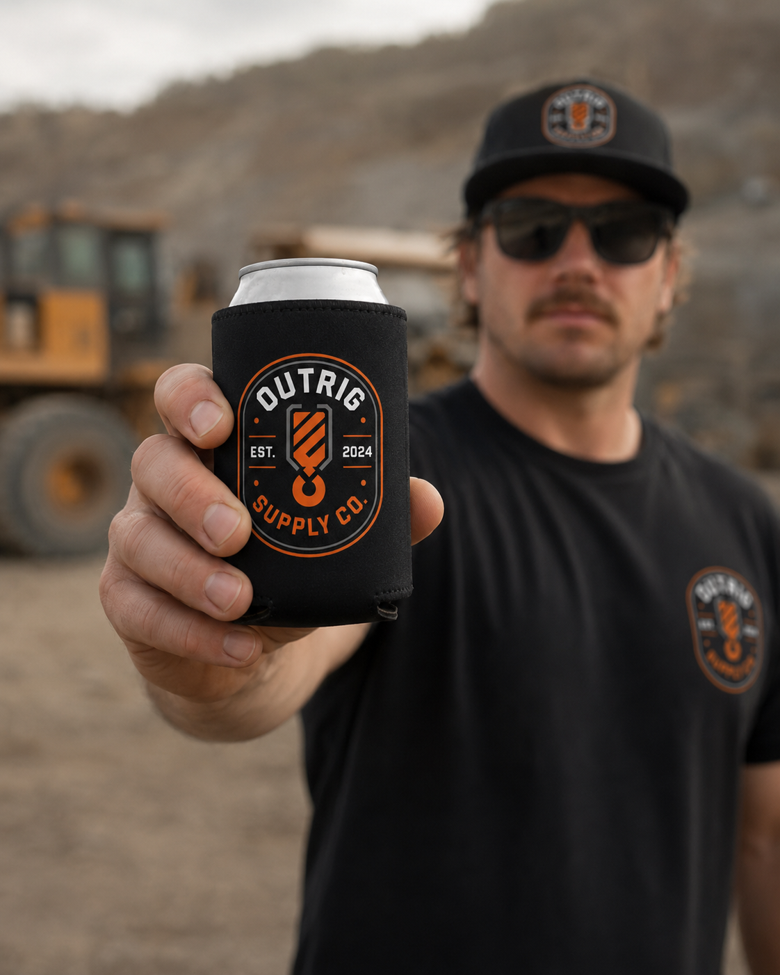 Man holding a can cooler with Outrig Supply Co branding in an outdoor setting.