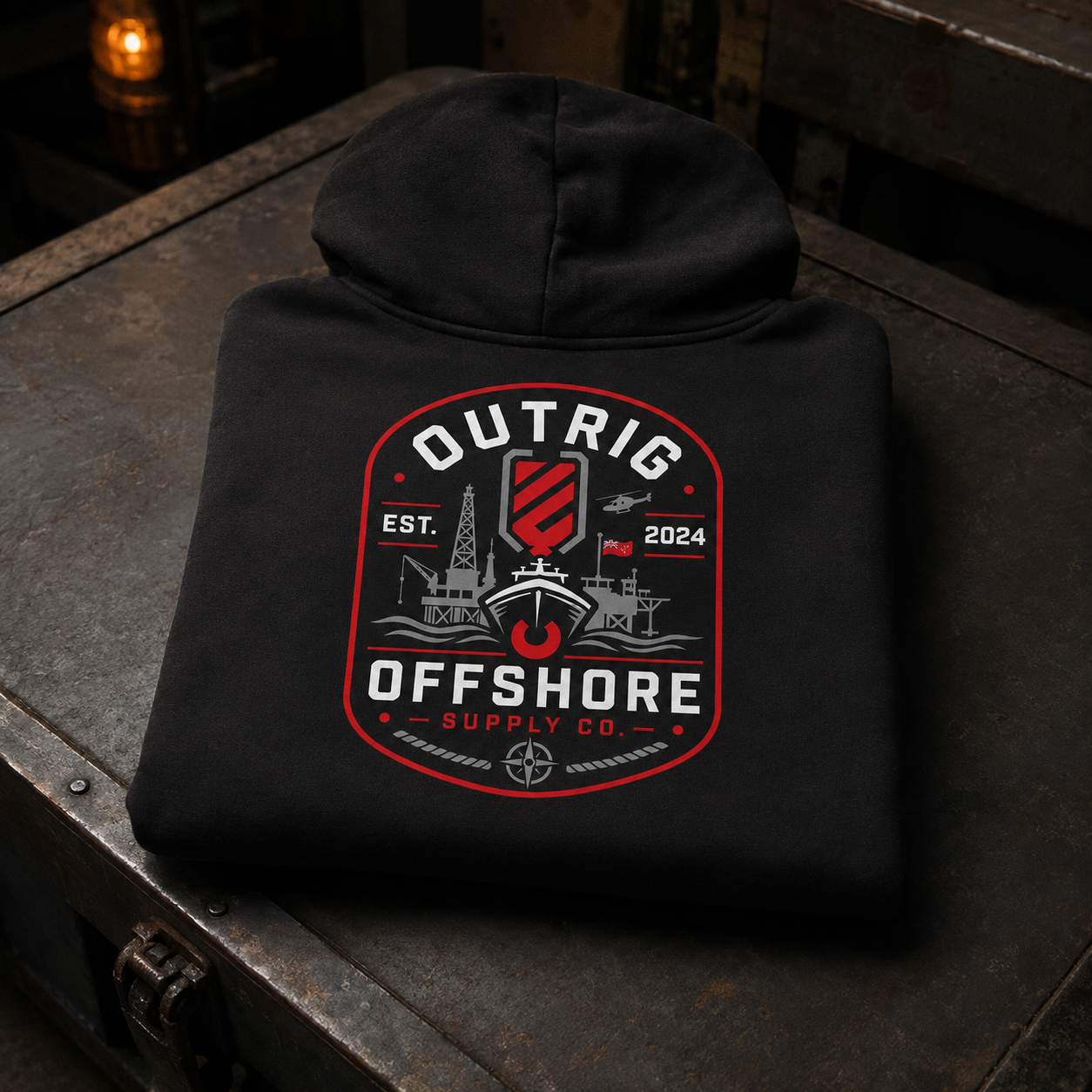 Folded black Outrig Offshore Crew Hoodie with the full offshore back artwork displayed on a dark steel workbench