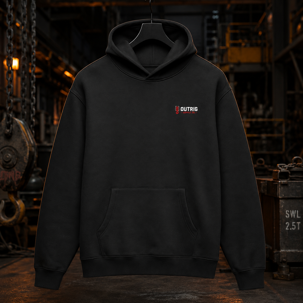 Front view of the black Outrig Offshore Crew Hoodie with small red and white chest logo in a dark industrial workshop