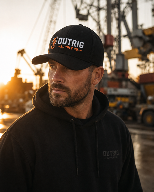 Outrig Core Flexfit Cap in black with orange-and-white Outrig Supply Co branding.