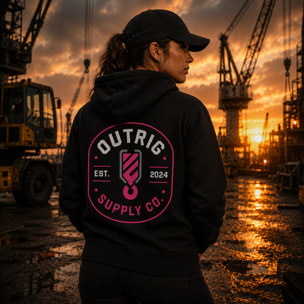 Person wearing a hoodie with 'Outrig Supply Co.' logo at a construction site during sunset.